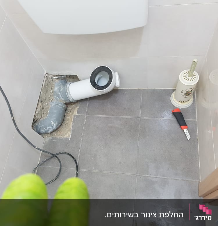 צינור ביוב פתוח עם כלי עבודה על הרצפה